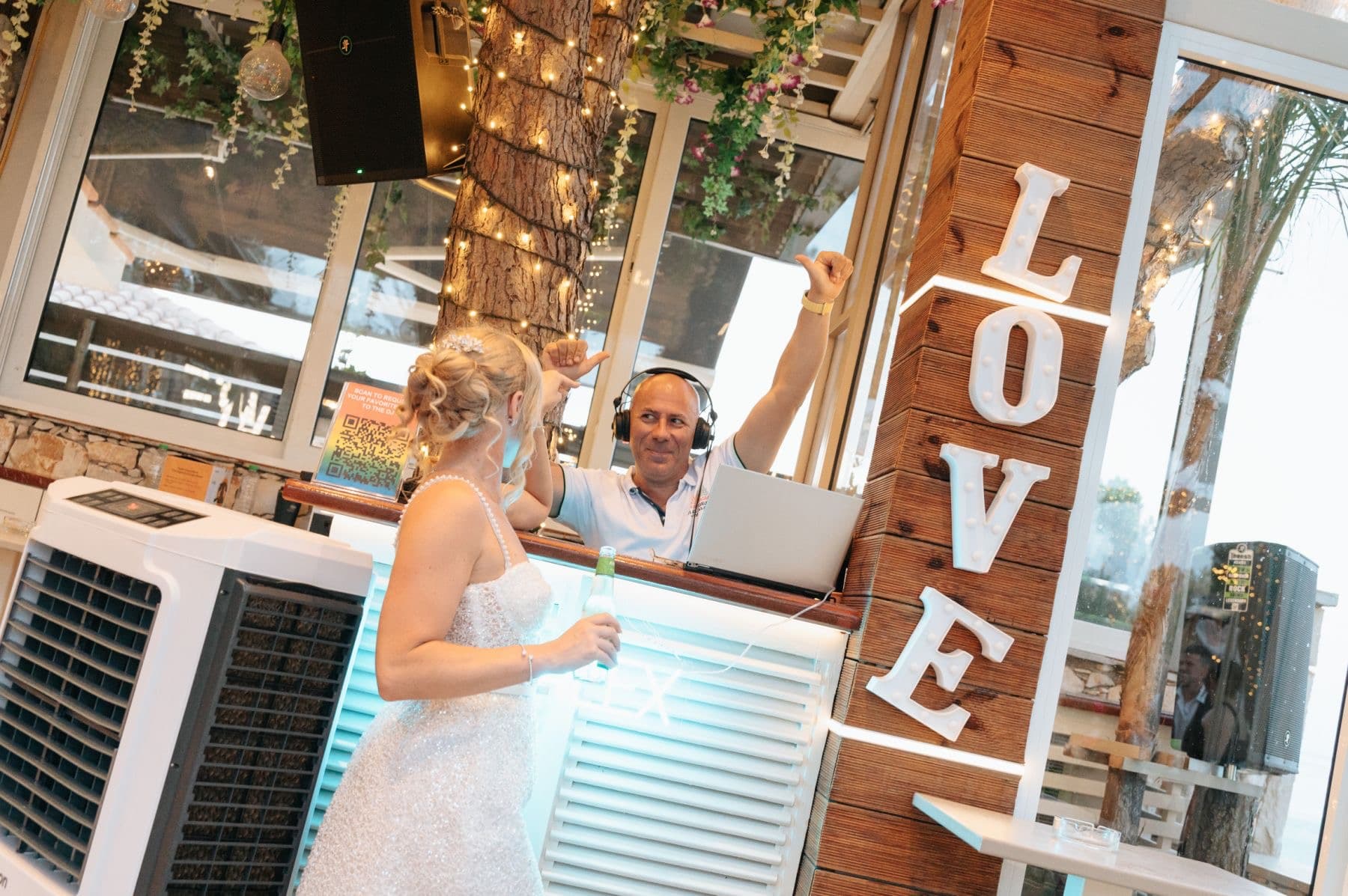 Bride at DJ booth with LOVE sign at Zakynthos wedding